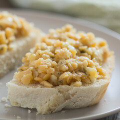 Fresh homemade vegan spread or salad made with split red lentil, onion, garlic and parsley, served on fresh homemade bread on plate (Selective Focus, Focus on the front of the lentils)