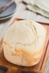 Fresh homemade loaf of white bread made by a bread making machine, served on wooden board...