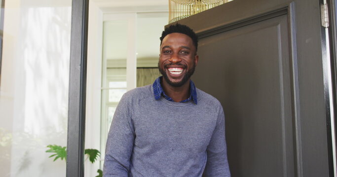Smiling man standing at front door, welcoming guests into cozy home