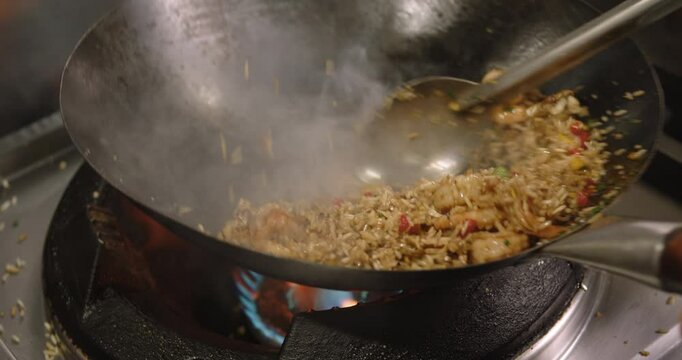 Close-up of a chef cooking Peruvian shrimp fried rice in a big pan