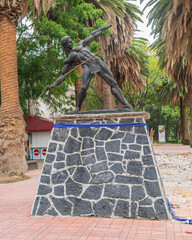 Heroic warrior sculpture and palm trees background