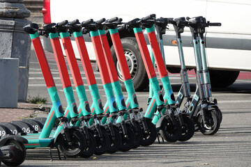 Electric scooters stand in a row