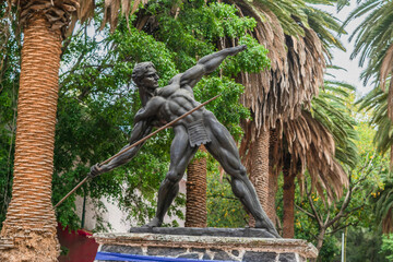 Heroic warrior sculpture and palm trees background
