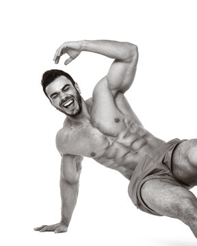 Muscular man in shorts posing in dynamic positions, laughing, exercising, and kneeling confidently. Monochrome photo emphasizes strength, fitness, and positive energy against clean white background