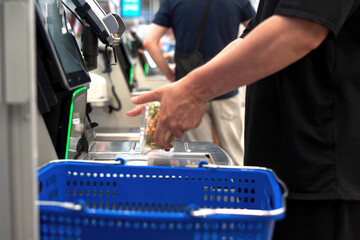 Shopper interacts with a self-checkout kiosk to scan groceries, close-up.
