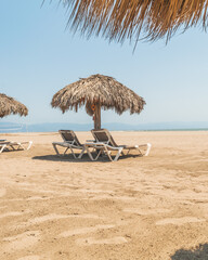 Palm roofs and resting chairs in the beach of Puerto Vallarta