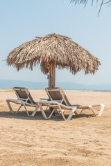 Palm roofs and resting chairs in the beach of Puerto Vallarta