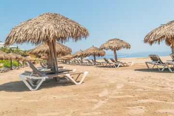 Palm roofs and resting chairs in the beach of Puerto Vallarta
