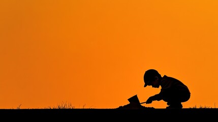 Child's silhouette playing in sand at sunset.