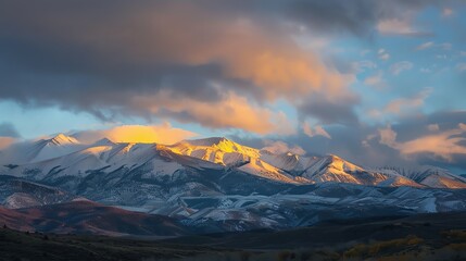 Obraz premium Snow-capped mountains at sunset with a golden glow.