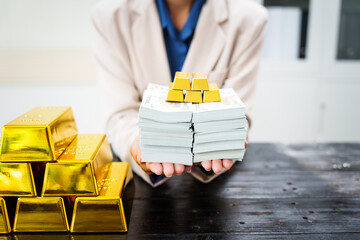 An Asian businesswoman sits at her desk analyzing gold bar prices, buying and selling gold, trading...