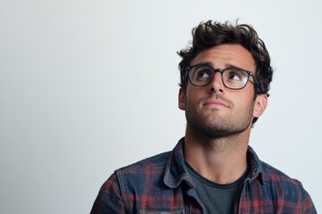 Fototapeta premium Thoughtful Young Man in Glasses with Casual Style Looking Upward