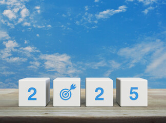 2025 letter with goal icon on white block cubes on wooden table over blue sky with white clouds, Happy new year 2025 success concept