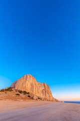 Naklejka premium Stunning view of rocky cliff and clear sky at sunset near coastal road
