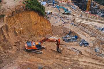 Excavator dig the ground in the foundation pit of building on a construction site. View from above