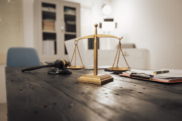 A lawyer's desk featuring a judge's hammer, an open notebook, and the Scales of Justice,...