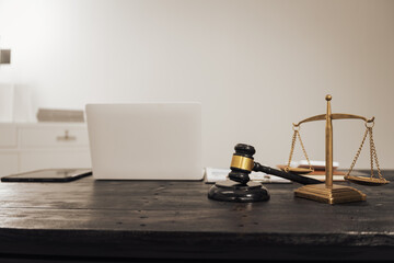 A lawyer's desk featuring a judge's hammer, an open notebook, and the Scales of Justice, symbolizing law, legal services, and criminal justice. No people are present