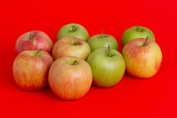 Apples on a red background. Red with yellow and green apples.
