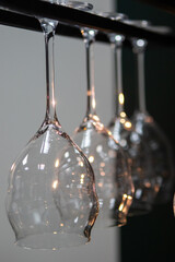 Elegant wine glasses hanging upside down on a rack with a soft focus on their reflective surfaces, creating a sophisticated and stylish atmosphere