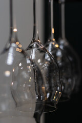 A close-up of hanging wine glasses with a reflective surface, showcasing intricate lighting reflections and transparency, perfect for a sophisticated and elegant bar atmosphere