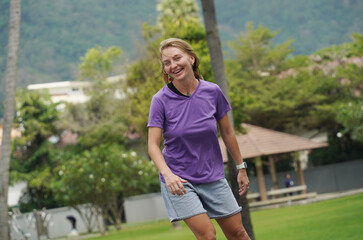 A woman is rollerblading gracefully on a road located in a park