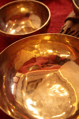 A detailed view of brass singing bowls with intricate engravings, reflecting warm tones and...