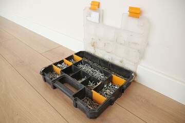 A wood flooring with a toolbox containing screws and drills