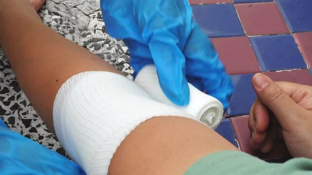 Video footage of a professional nurse demonstrating how to wrap a patient's arm with an elastic bandage during a home visit.