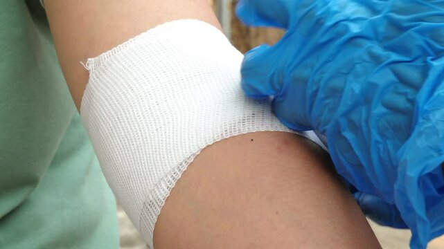 Video footage of a professional nurse demonstrating how to wrap a patient's arm with an elastic bandage during a home visit.