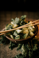 Delightful Pickled Cucumbers Garnished With Fresh Herbs and Sushi Sticks Served in a Rustic Bowl for a Unique Dining Experience