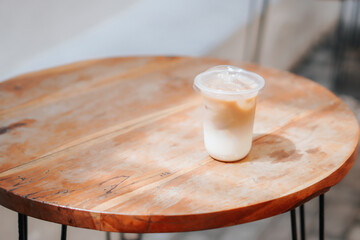 A refreshing glass of iced coffee sits on a wooden table, perfect for a sunny day. The image captures the drink's cool, refreshing appeal, perfect for cafes, food blogs, and lifestyle content.