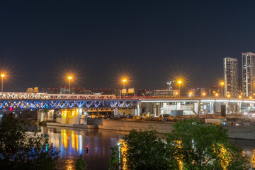 Fototapeta premium The scyscrapers of the Moscow City at night and the Dorogomilovsky bridge with illumination. Translation of text - street names: Krasnopresnenskaya, center, etc.