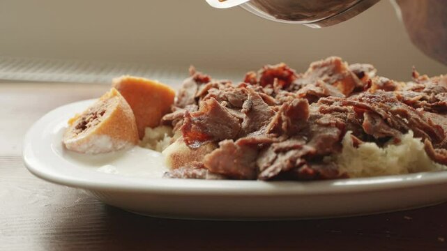 Local Turkish dish Iskender doner on an oval plate in slow motion
