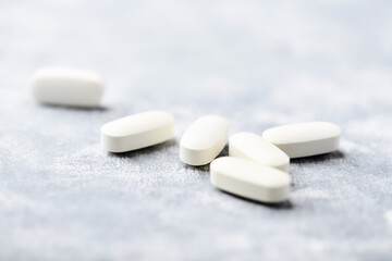 Arginine alpha-ketoglutarate (AAKG) tablets. Bodybuilding food supplements on wooden background. Soft focus. Close up. Copy space.