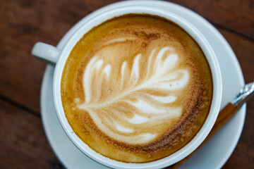 Close-up photo of hot coffee latte with milk on wooden dining table in the morning.