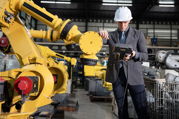 Business or engineer Caucasian male checking with control  a robot arm with remote computer