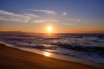 Monterey Bay Sunset Red. Beachfront with gentle waves and solitary seagull in the distance.