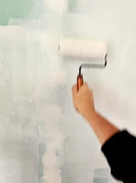 Gros plan d'une personne peignant un mur avec un rouleau &agrave; peinture