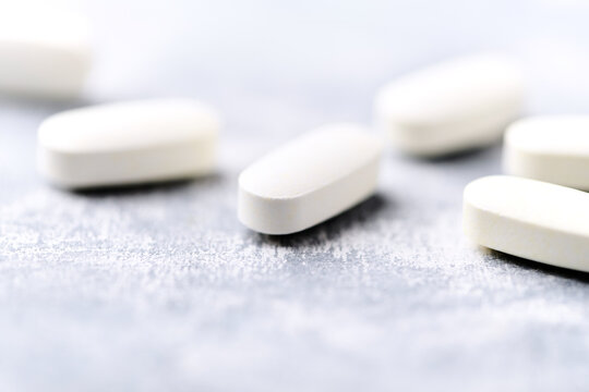 Arginine alpha-ketoglutarate (AAKG) tablets. Bodybuilding food supplements on wooden background. Soft focus. Close up. Copy space.