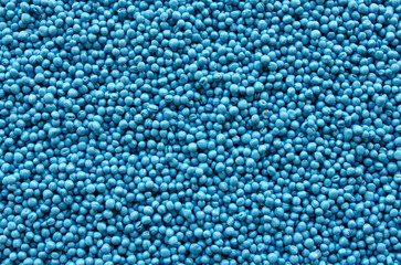 Treated rapeseed with blue coating, background, texture, top view. Encrusted rapeseed ready for sowing. Background of treated rapeseed, blue color, texture, top view.