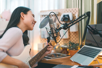 Asian woman composer playing guitar single song with microphone at home studio