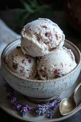 A bowl of three scoops of ice cream with nuts and lavender accents.