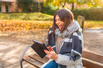Obraz premium Woman laughing while using digital tablet in a park