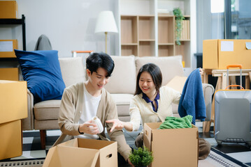 Fototapeta premium Young couple organizing belongings in a cozy home with boxes and luggage. Perfect for themes of moving