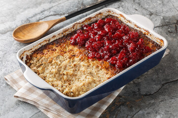 Spicy sweet Maksalaatikko creamy rice liver casserole served with cranberry jam close-up in baking dish on table. Horizontal