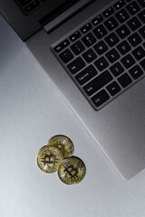 Gold bitcoin coins, laptop keyboard close up.