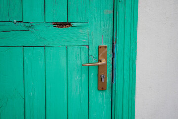 Yellow metal door handle on green wooden colored doors