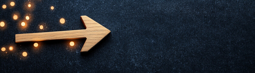 Wooden arrow on dark surface with golden lights, symbolizing direction and guidance.