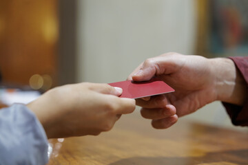 Close-up of a pair of caucasian hands handing over the hotel room electronic card. At the hotel reception, a woman hands her personal document to the receptionist to make the reservation.