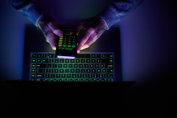 Male hands are using calculator on mobile phone and laptop keyboard.